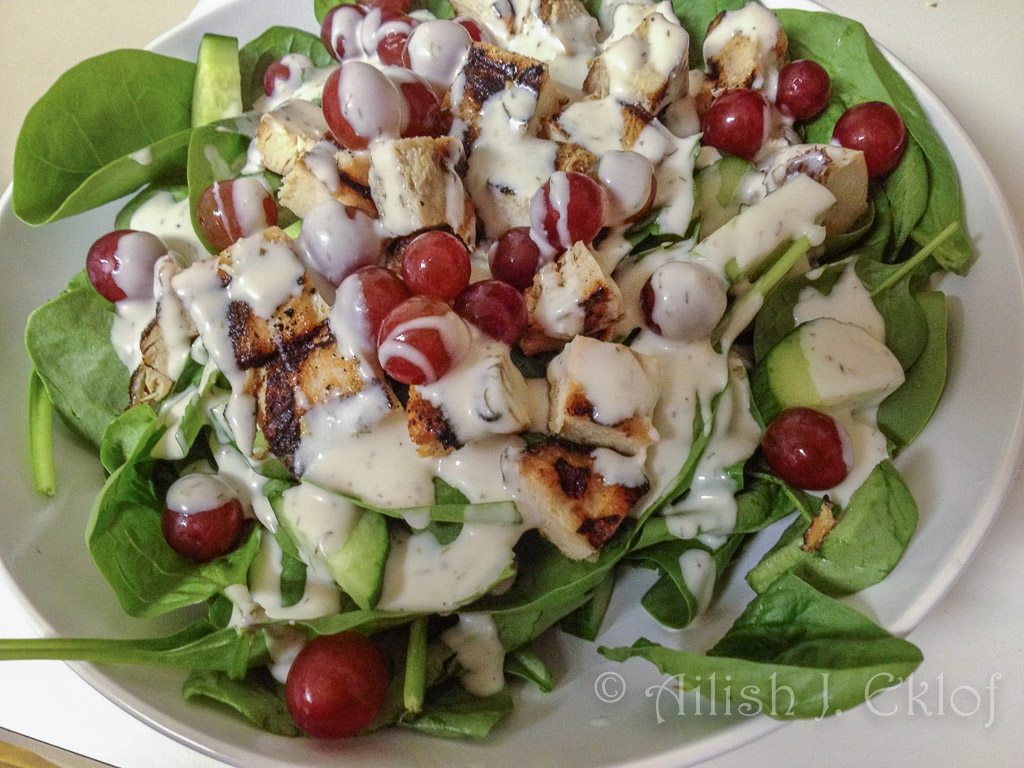 Salad of spinach, chicken, cucumbers, and grapes.